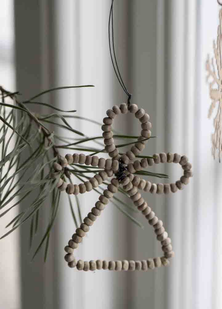 Julgranspynt i form av en hängande ängel av ljusa träpärlor med en höjd på 7,5 centimeter och en längd på 6 centimeter. 
