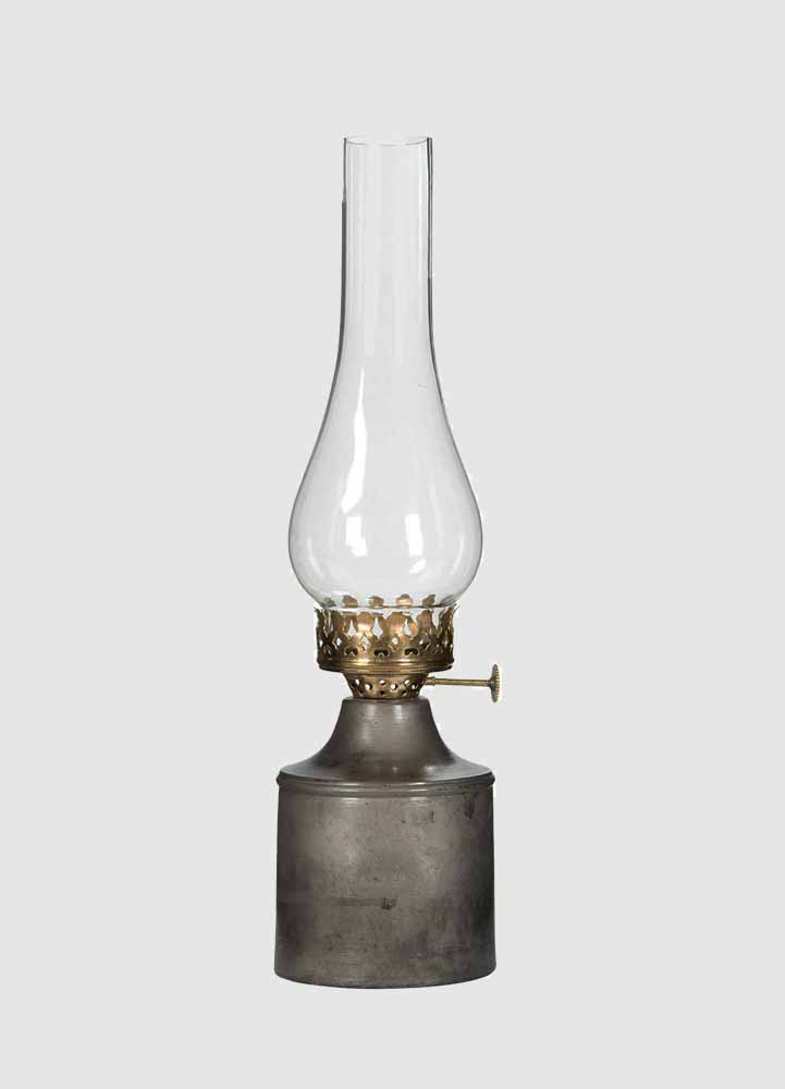 Oljelampa som påminner om en fotogenlampa med metallbotten och brännarrör i ofärgat glas med mässingplats för ljus, gjord för värmeljus.
