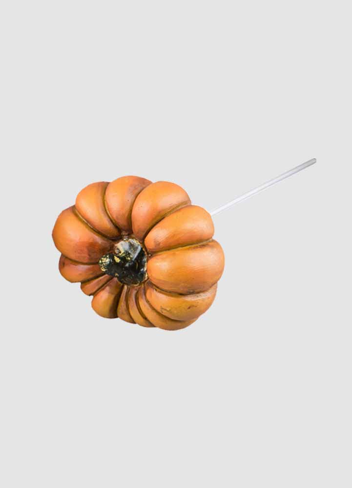 Halloweenpynt, en liten orange konstgjord pumpa på sex centimeter liggandes ner med en vit bakgrund. 
